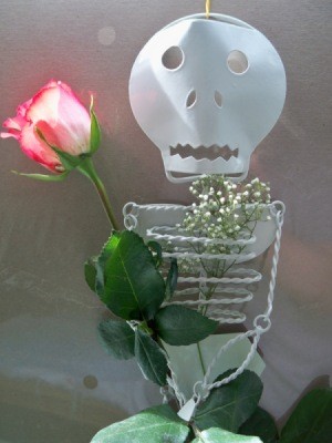 A metal skeleton sculpture with a rosebud.