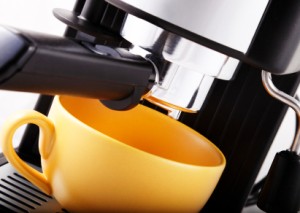closeup of espresso machine and orange coffee cup