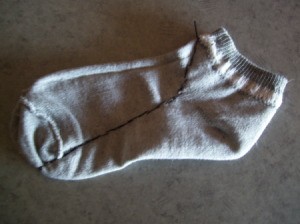 A single gray ankle sock, inside out.
