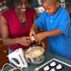 A mother showing her son how to crack an egg.