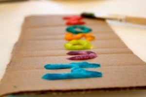 Sidelong view of puffy paint letteing on cardboard strip.