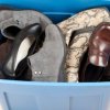 Pile of shoes in blue storage container.