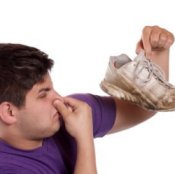 Picture of a man holding up stinky shoes.