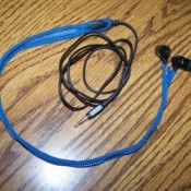 blue zippered earbud cord case with earbuds inside ling on a table