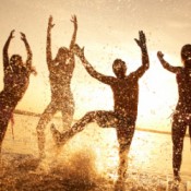 People playing on the beach at sunset.