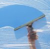 Hand holding a squeegee swiping soap off a window.
