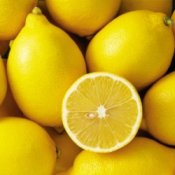Half a lemon on a pile of whole lemons.
