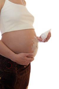 A pregnant woman rubbing cream in her belly to prevent stretch marks.
