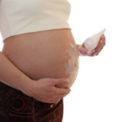 A pregnant woman rubbing cream in her belly to prevent stretch marks.