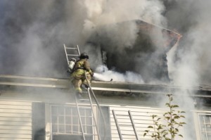 A firefighter in the smoke from a house fire.