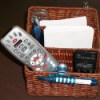 A basket with TV remotes, pens, paper and other small useful tools.