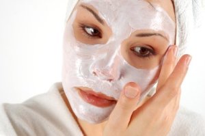 A woman applying a face mask at home.