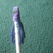 A pencil topper with a funny face and hair.