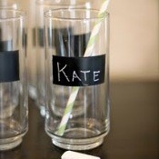 Tall Glasses with black stripe of chalkboard painted on them. The glass centered inthe image has Kate written on it, a yellow striped straw in the glass and a piece of chalk laying in front. 