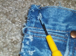 Close up of seam ripper next to jeans