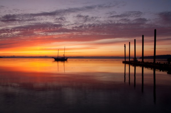 A colorful sunrise over the Puget Sound, with a boat and dock.