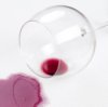 Glass of red wine spilled on white tablecloth.