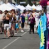 A street fair with tie dyed t-shirts for sale.