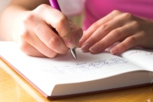A woman writing in a diary.