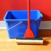Mop and bucket leaning up against a red wall.