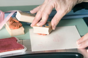 A crafter using rubber stamps to decorate a handmade card.