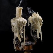 Smoking, melted candles against a black background.