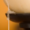 Candle wax dripping down side of container and wood stand