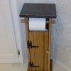 A bathroom toilet paper holder that is built like an outhouse.