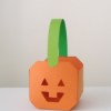 Small paper paper pumpkin basket. Pumpkin is orange, handle is green.