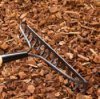A rake laying on garden mulch.
