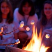 Girls roasting marshmallows over a campfire while camping.