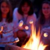 Girls roasting marshmallows over a campfire while camping.