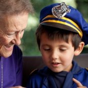 A young boy wearing a policeman costume, sitting with his grandmother.