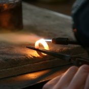 Photo of a jeweler heating a gold ring with a torch.