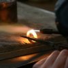 Photo of a jeweler heating a gold ring with a torch.