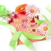 Paper with letters spelling Happy Mother's Day, ribbon, flowers, and glitter hearts