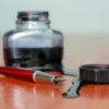 Spilled ink on wood surface. There is also an open bottle and a pen.