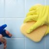 Picture of someone cleaning tile with a spray bottle and a sponge.