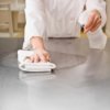 Someone cleaning a kitchen counter with cleaner.