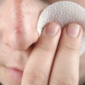 Someone using an acne cleansing pad on their face.