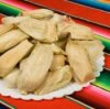 Tamales on white plate sitting on a zarape style tablecloth.
