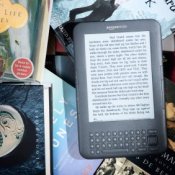 Photo of a Kindle surrounded by books.