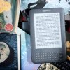Photo of a Kindle surrounded by books.