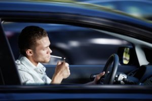 Man Lighting a Cigarette in his Car While Driving