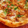 Corner of a BBQ chicken pizza.