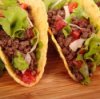 Two tacos with lettuce and cheese.