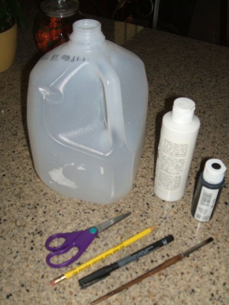 Supplies for milk jug ghoast. One gallon milk jug, scissors, paint brush, white and black acrylic paint, black marker.
