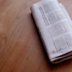 A newspaper on a wood table.