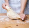 A woman kneading pizza dough.