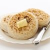 Crumpets on a plate with butter on them.